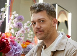 Hairdresser Michael Grey standing in front of a bouquet of flowers
